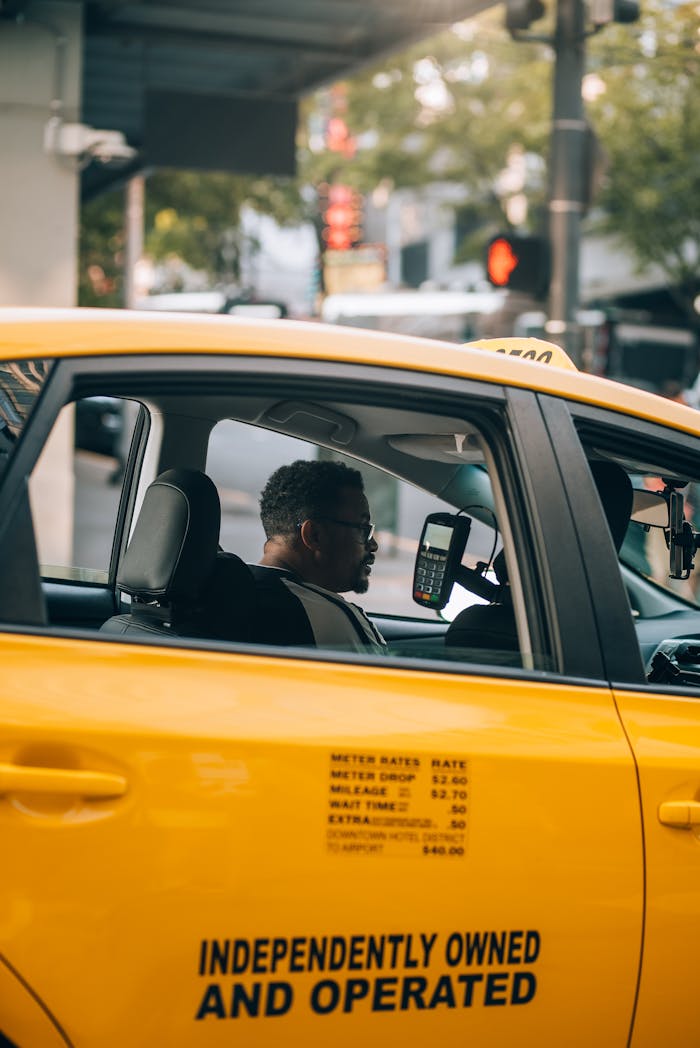 Yellow taxi in city street with driver, reflecting urban transportation and lifestyle.